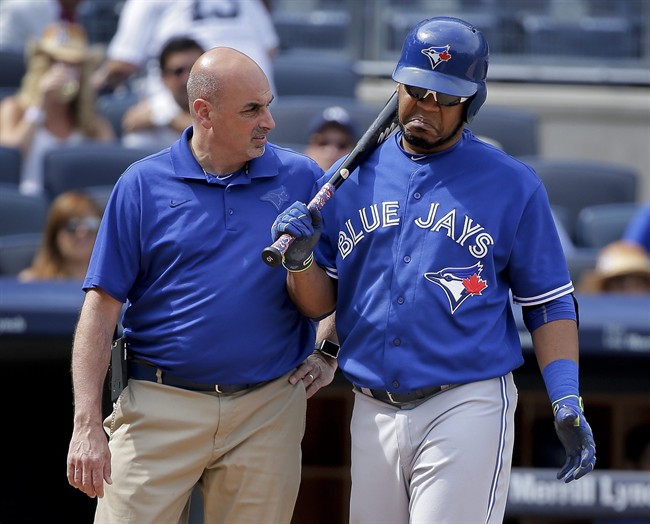 Toronto Blue Jays' Edwin Encarnacion, right, shrugs off questions from a trainer during an at-bat against the New York Yankees during the eighth inning of a baseball game, Saturday, Aug. 8, 2015, in New York.