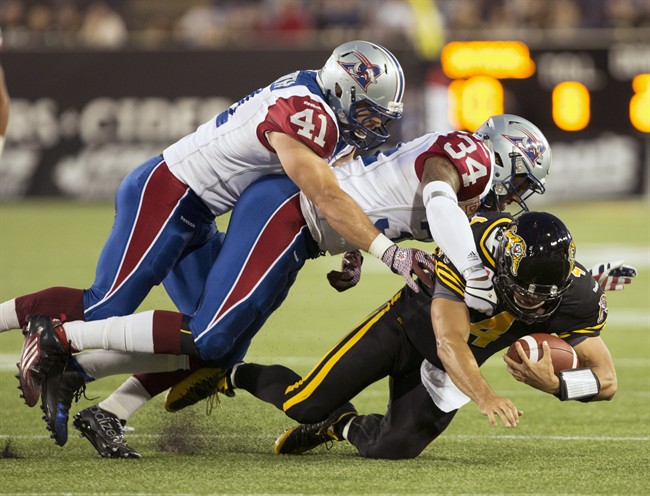 Hamilton Tiger-Cats' Zach Collaros, right, is tackled by Montreal Alouettes' Kyries Hebert, centre, and Kyler Elsworth during the first half of CFL football action in Hamilton, Ont., on Thursday, August 27, 2015.