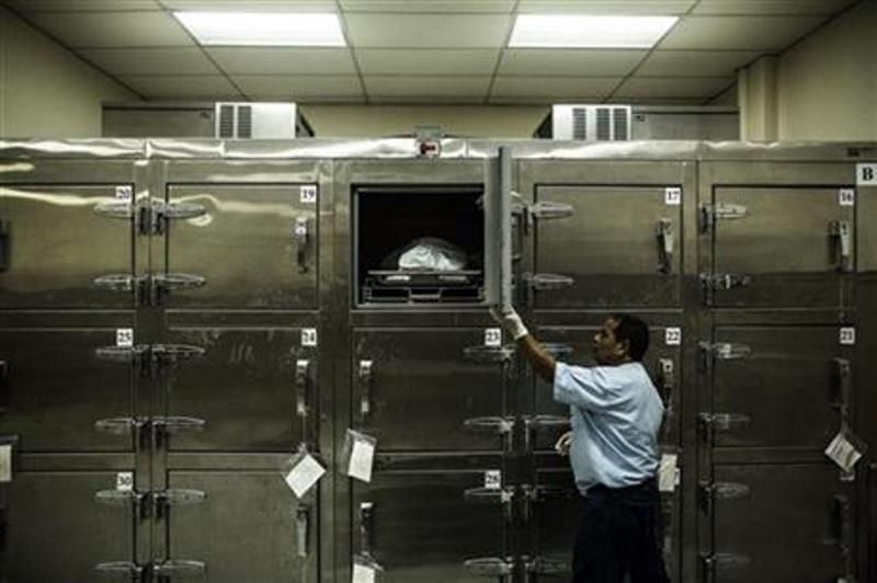  In this May 26, 2015 file photo, a forensic worker closes a morgue refrigerator door after placing a suspected gang member's body inside at the Institute of Legal Medicine in San Salvador, El Salvador. 