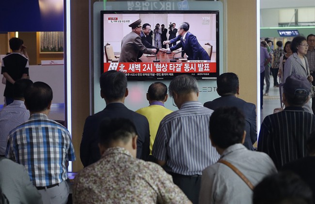 People watch a TV news program reporting South and North Korea reached an agreement, at the Seoul Railway Station, South Korea, Tuesday, Aug. 25, 2015.