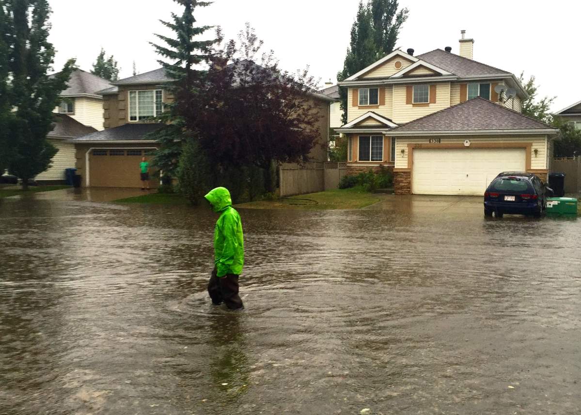 A clogged storm drain causes a street to flood in Douglasdale on Tuesday, August 4, 2015.