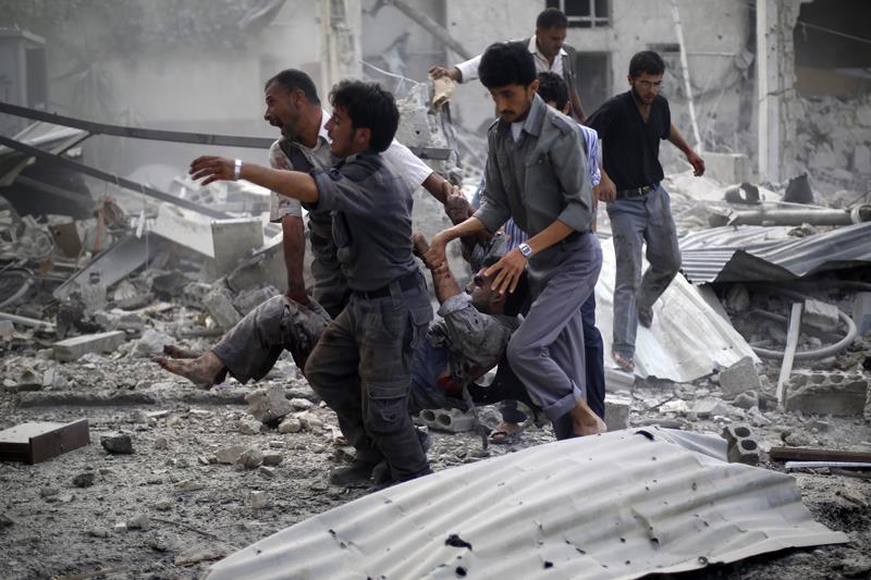 Syrian emergency personnel carry a wounded man following air strikes by Syrian government forces on a marketplace in the rebel-held area of Douma, east of the capital Damascus, on August 16, 2015.