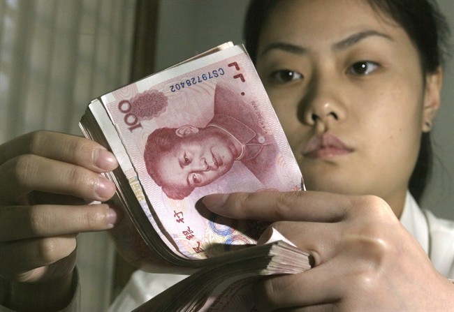 A Chinese bank worker displays Chinese yuan at a bank in Beijing.