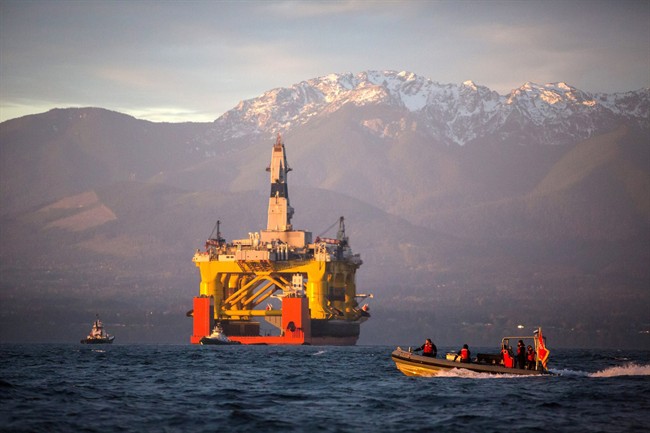 In this April 17, 2015 file photo, with the Olympic Mountains in the background, a small boat crosses in front of the Transocean Polar Pioneer, a semi-submersible drilling unit that Royal Dutch Shell leases from Transocean Ltd., as it arrives in Port Angeles, Wash., aboard a transport ship after traveling across the Pacific before its eventual Arctic destination. 