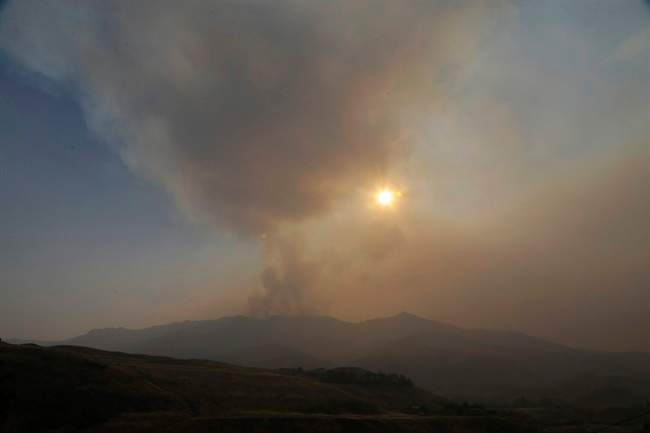 Smoke rises from a ridge above Pateros, Wash., as the sun sets Tuesday, Aug. 25, 2015. The town is located in between where wildfires are currently burning in Chelan, Wash., and Okanogan, Wash., but Pateros suffered the loss of hundreds of homes in fires that hit the area in 2014. 
