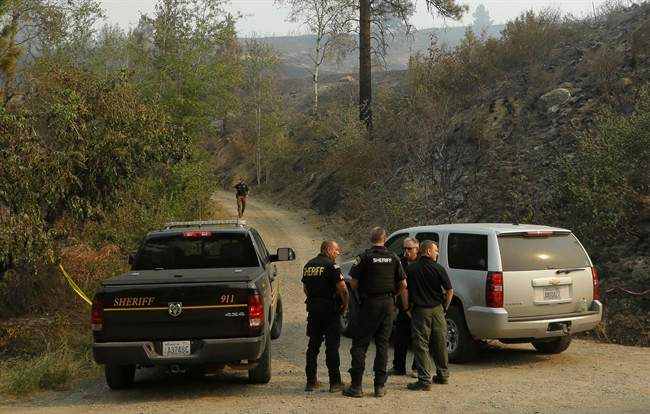 Okanogan County Sheriff's deputies guard the entrance to Woods Canyon Road near Twisp, Wash. Thursday, Aug. 20, 2015. Three firefighters were killed Wednesday along the road while fighting a wildfire. 