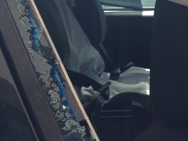 Car windown is broken after child is rescued from locked vehicle on hot day.