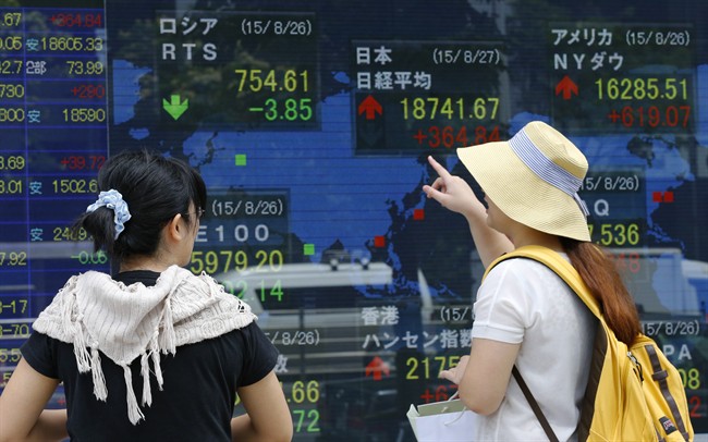 Women look at an electronic stock indicator of a securities firm in Tokyo, Thursday, Aug. 27, 2015. Asian stocks rose Thursday after Wall Street soared overnight, breaking a six-day string of losses. 