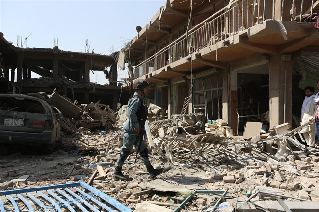 An Afghan police officer walks at the site of a car bomb attack in Kabul, Afghanistan, Friday, Aug. 7, 2015. 