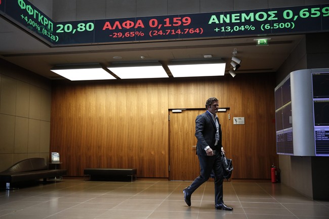 A man walks at the reception hall of the Athens' Stock Exchange as stock prices are on display on a ticker screen in Athens, Greece, on Tuesday, Aug. 4, 2015.
