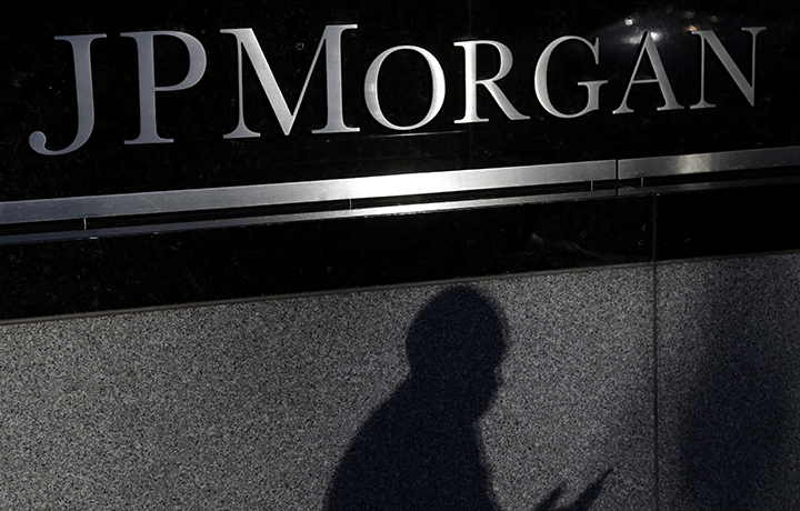 The shadows of a pedestrian is cast under a sign in front of JPMorgan Chase & Co. headquarters in New York.