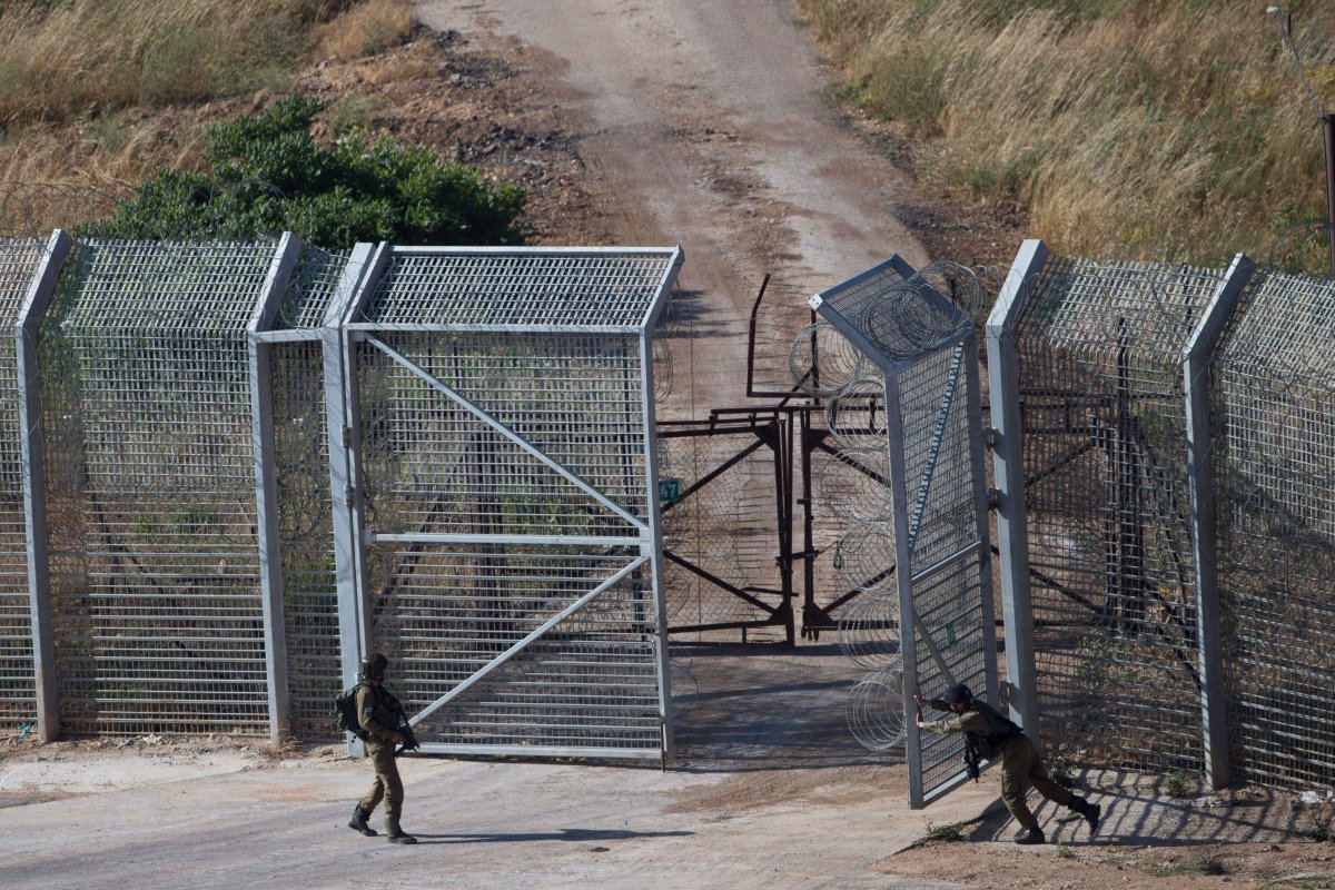 In this photo taken Sunday, June 21, 2015, Israeli soldiers close a border gate after a U.N. vehicle crossed into an area near the Druze village of Khader in Syria, seen from the Israeli-controlled Golan Heights. 