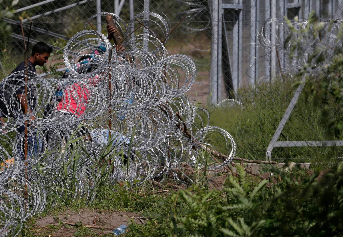 Migrants try to cross under a wire fence on the Serbian border with Hungary, near the village of Hajdukovo, Serbia, Monday, Sept. 7, 2015.