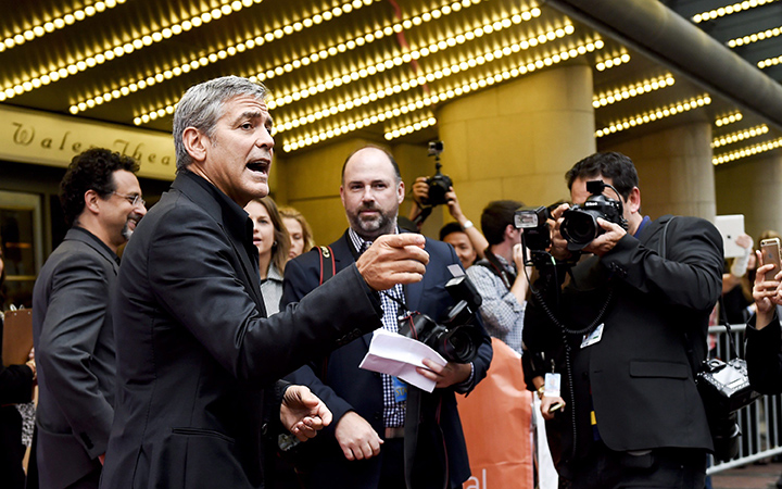 Producer George Clooney, left, points to photographers on the red carpet for the new movie 'Our Brand Is Crisis' during the 2015 Toronto International Film Festival in Toronto on Friday, September 11, 2015.