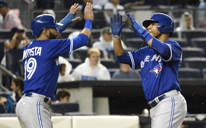 Toronto Blue Jays' Jose Bautista and  Edwin Encarnacion high five at home plate after scoring on Russell Martin's double off of New York Yankees starting pitcher Ivan Nova in the second inning in Game 2 of a doubleheader baseball game at Yankee Stadium, Saturday, Sept. 12, 2015, in New York.