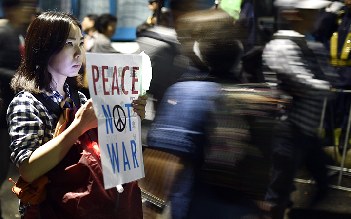 A young woman holds a placard protesting against controversial military reform bills outside Japan's parliament in Tokyo, Japan, 18 September 2015.