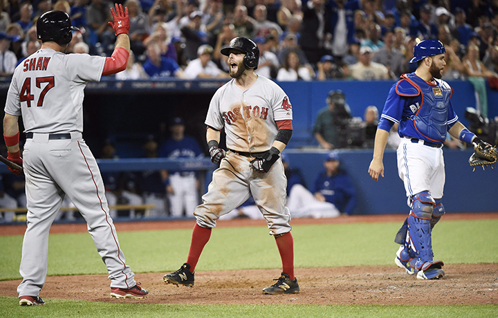 Boston Red Sox second baseman Dustin Pedroia, centre, celebrates with teammate Travis Shaw after sliding safe pass Toronto Blue Jays catcher Russell Martin, right, to take the lead during ninth inning AL baseball action in Toronto on Saturday, September 19, 2015.