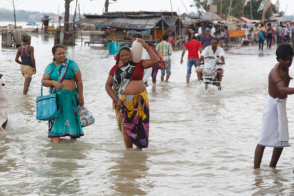 Hindu devotees walk from the flooded banks of river Ganga after heavy monsoon rains that caused the rise of water levels in Allahabad. (Photo by Ravi Prakash/Pacific Press/LightRocket via Getty Images).