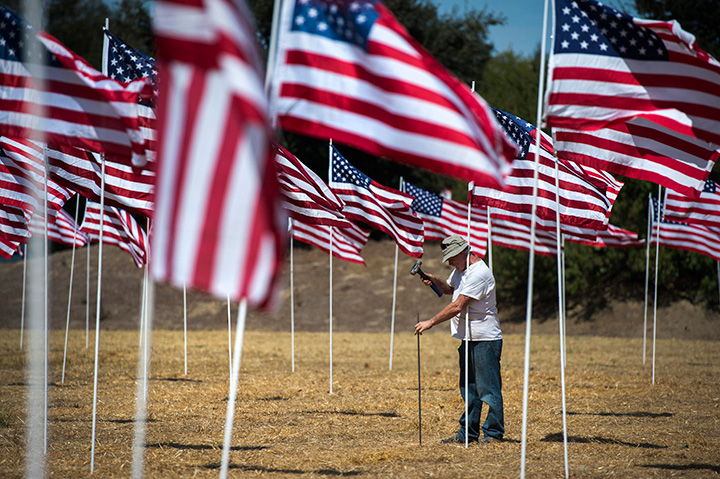 Jerry Shockley pounds a hole to place one of the 500 flags as part of a Sept. 11 Memorial Flag Tribute erected every year by John Vinson and his friends and family, Thursday, Sept. 10, 2015 in West Sacramento, Calif.