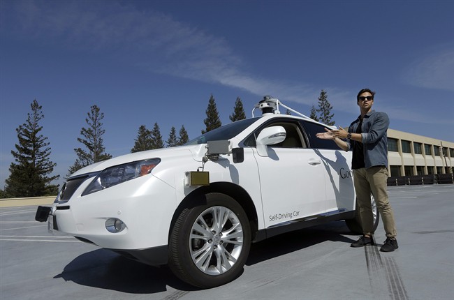 In this Monday, Aug. 24, 2015 photo, Brian Torcellini, Google team leader of driving operations, poses for photos next to a self-driving car at a Google office in Mountain View, Calif. Google employs a few dozen "safety drivers” that grab the steering wheel or hit the brakes on a fleet of robot cars that Google’s engineers are programming to navigate the roads without human assistance.