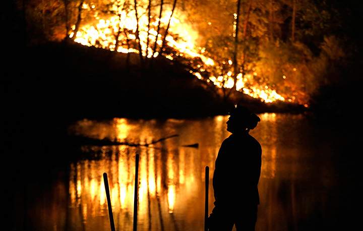 A firefighter stands near a wildfire in Middletown, Calif., on Sunday, Sept. 13, 2015.