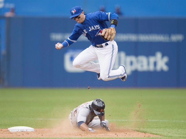 Toronto Blue Jays' Troy Tulowitzki, top, leaps over a sliding Detroit Tigers' Anthony Gose during eighth inning MLB baseball action in Toronto on Saturday, August 29, 2015. Tulowitzki says he's close to returning to the Toronto Blue Jays' lineup and is confident he'll get into a game before the end of the regular season.