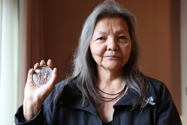 Chief Liz Logan, Fort Nelson First Nation, is shown in this handout photo in Vancouver, holding an original Treaty 8 medallion that was given to her great grandfather when he signed the treaty on her First Nations' behalf, on Tuesday Sept. 8, 2015. People once paddled from great distances to set up fishing camps on Liz Logan's family land in northern British Columbia, but today she says industrial pollution in the water has forced her to face off against the Crown.