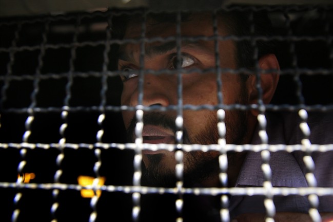 One of the men accused in the 2006 Mumbai train bombings looks from a police van as he is taken from a prison to a court in Mumbai, India, Wednesday, Sept. 30, 2015. An Indian court has sentenced five suspected Islamic militants to death and given seven others life in prison for bombing attacks nine years ago on seven Mumbai commuter trains that killed 188 people and wounded more than 800. (AP Photo/Rafiq Maqbool).