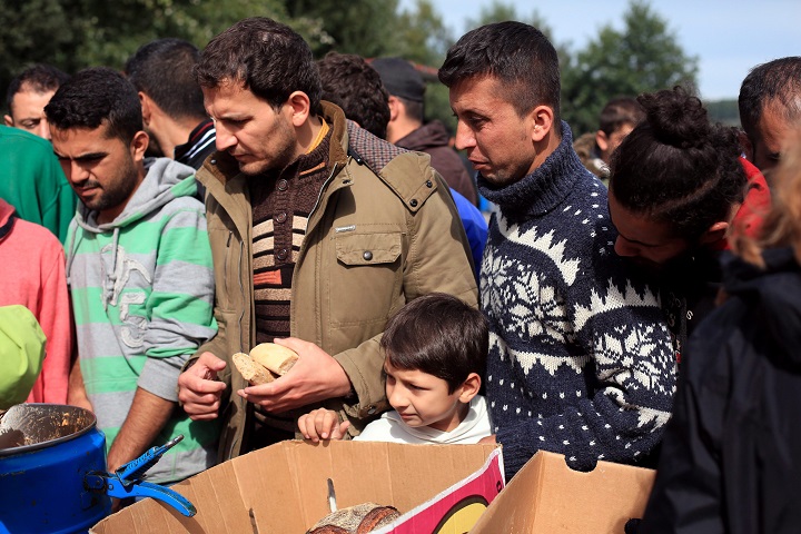 In this photo taken Thursday, Sept. 17, 2015, migrants queue during a food distribution in the migrant camp of Teteghem, outside Dunkirk, northern France. More than 1000 migrants fleeing conflict zones or poverty are based at the rapidly growing camp outside Dunkirk. All hope to make it across the English Channel to Britain.