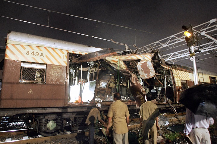 Railway workers and official clear the debris of the first class compartment of a local train which was ripped open by a bomb blast at Khar Mumbai, late 11 July 2006.  