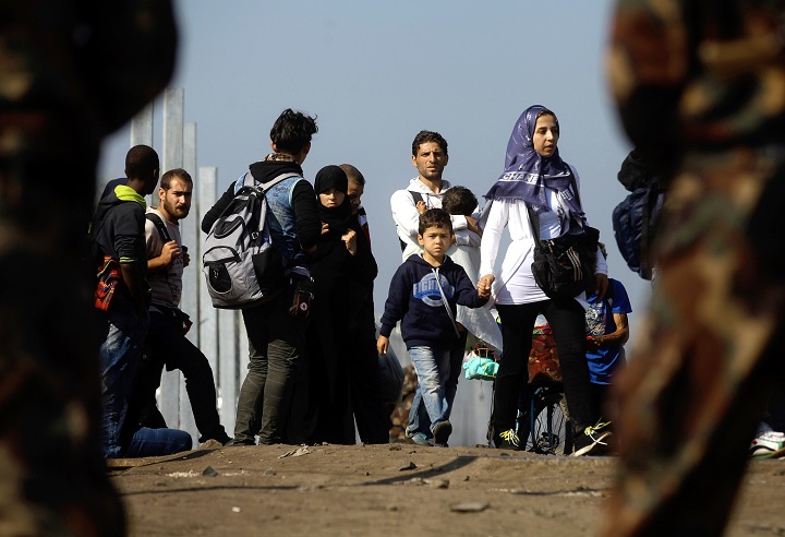 Hungarian soldiers stand guard as migrants  cross the border line between Serbia and Hungary near Roszke village on September 13, 2015. The number of migrants entering Hungary has hit a new one-day record, police said Sunday, as the country prepares to impose a controversial new law to stop the influx. 