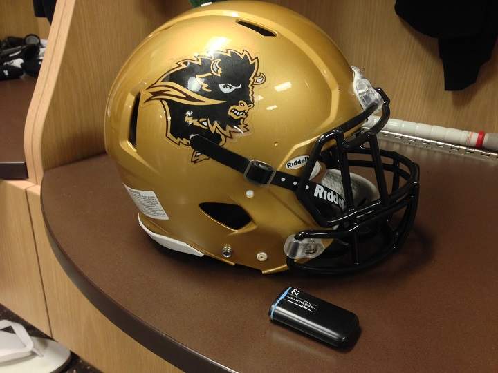A GPS player tracker lies beside a Manitoba Bisons football helmet.