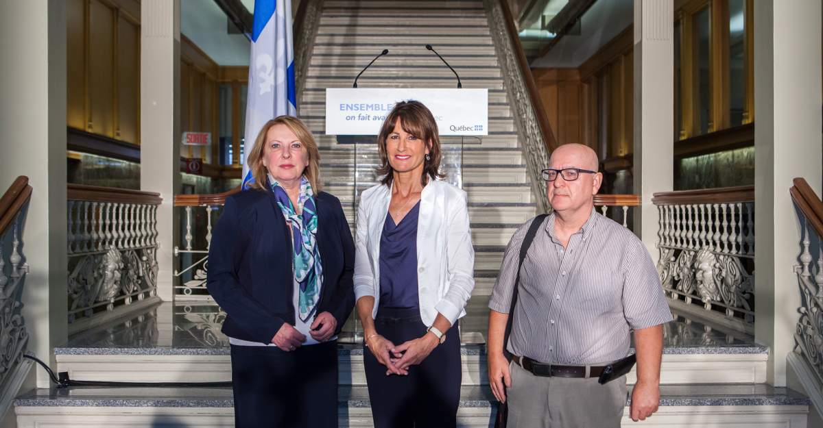 Immigration Minister Kathleen Weil stands with Christine St-Pierre and Father Mario Brisson, Monday, September 7, 2015.