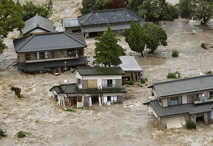 People inside houses wait to be rescued as the houses are submerged in water flooded from a river in Joso, Ibaraki prefecture, northeast of Tokyo Thursday, Sept. 10, 2015.