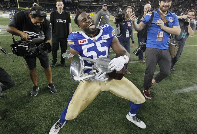 Winnipeg Blue Bombers' Jamaal Westerman (55) strums the Banjo Bowl after defeating the Saskatchewan Roughriders in CFL action in Winnipeg Saturday, September 12, 2015.