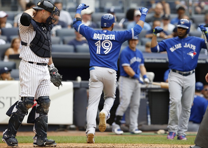 New York Yankees catcher Brian McCann, left, reacts as Toronto Blue Jays Jose Bautista (19) celebrates heading to the dugout after hitting an eighth-inning, solo, home run as on-deck-batter Edwin Encarnacion right, joins the celebration during the first baseball game of a doubleheader at Yankee Stadium in New York, Saturday, Sept. 12, 2015. 