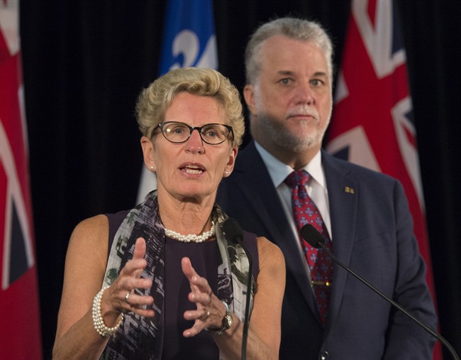Ontario Premier Kathleen Wynne speaks at a news conference while Quebec Premier Philippe Couillard, right, looks on, Friday, September 11, 2015 at the beginning of a joint cabinet meeting between Ontario and Quebec in Quebec City. THE CANADIAN PRESS/Jacques Boissinot.