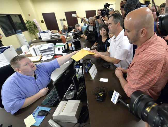 Rowan County deputy clerk Brian Mason, left, hands James Yates, and his partner William Smith Jr., their marriage license at the Rowan County Judicial Center in Morehead, Ky., Friday, Sept. 4, 2015.