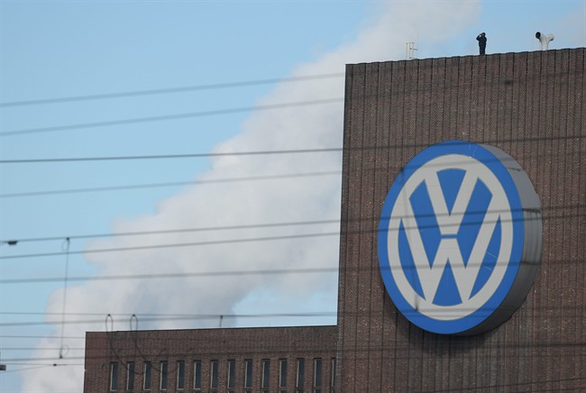 A man looks through binoculars as he stands next to a corporate logo of Volkswagen on the rooftop of the former power plant of the German car manufacturer in Wolfsburg, Germany, Friday, Sept. 25, 2015. 