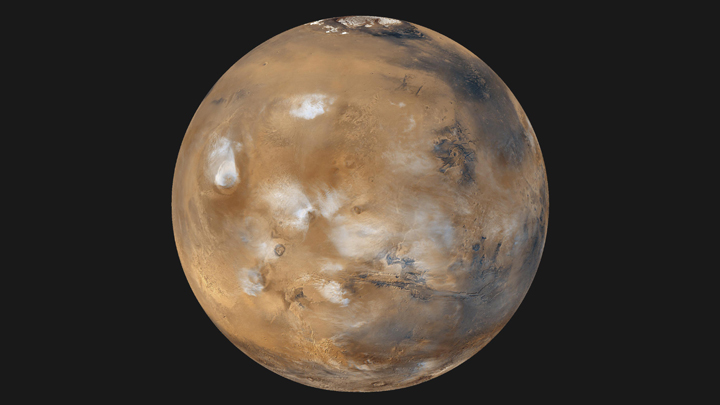 The ice caps of Mars along with the bluish-white water ice clouds hang above the Tharsis volcanoes.