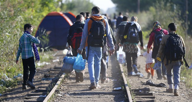 People make their way on the railway track at the border line between Serbia and Hungary near Roszke, southern Hungary, Wednesday, Sept. 9, 2015. 