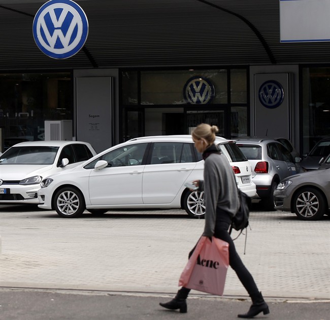 A woman walks by a Volkswagen dealer in Milan, Italy, Sunday, Sept. 27, 2015. German media report that Volkswagen received warnings years ago about the use of illegal tricks to defeat emissions tests. The automaker admitted last week that it used special software to fool U.S. emissions tests for its diesel vehicles. 