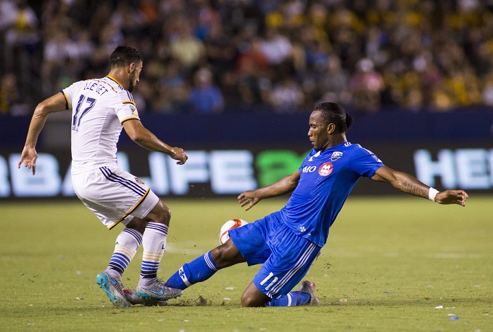 Montreal Impact forward Didier Drogba, right, fights for the ball against Los Angeles Galaxy defender Dave Romney in the first half of an MLS soccer game in Carson, Calif., Saturday, Sept. 12, 2015.