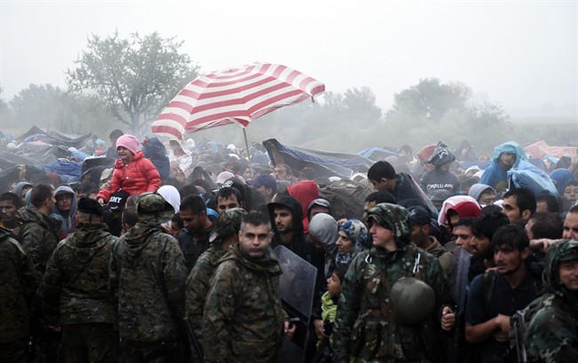 Refugees and migrants wait to pass from the northern Greek village of Idomeni to southern Macedonia, Thursday, Sept. 10, 2015. Thousands of people, including many families with young children, braved torrential downpours to cross Greece’s northern border with Macedonia early Thursday, after Greek authorities managed to register about 17,000 people on the island of Lesbos in the space of a few days, allowing them to continue their journey north into Europe. (AP Photo/Giannis Papanikos).