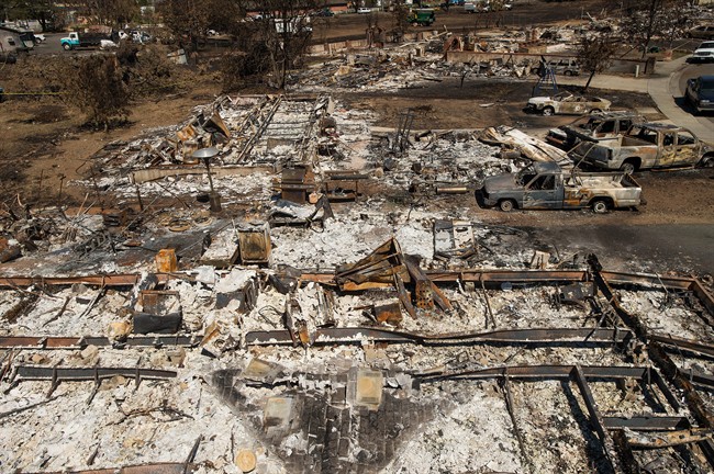 FILE- This Sept. 21, 2015, file photo shows shows remains of homes and vehicles scorched by a wildfire in Middletown, Calif. 