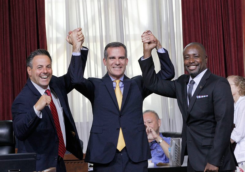 Councilman Joe Buscaino, left, with Los Angeles Mayor Eric Garcetti, center, and Councilman Marqueece Harris-Dawson celebrate after a city council vote in Los Angeles on Tuesday, Sept. 1, 2015. 