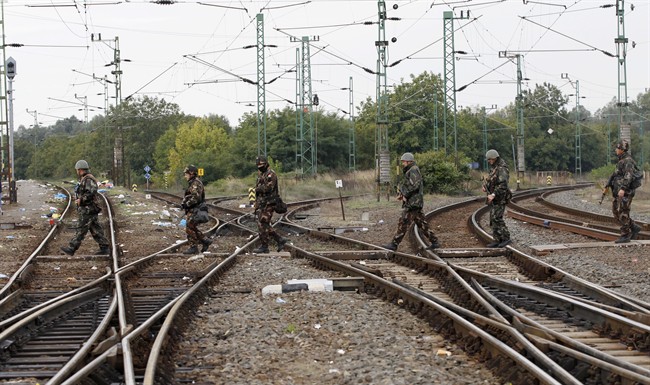 Hungarian soldiers cross train track at a station in the village of Zakany, Hungary, Saturday, Sept. 26, 2015. Conciliation replaced confrontation among European nations which have clashed over their response to a wave of migration, as thousands of asylum seekers streamed into Croatia on Saturday in hopes of chasing a new future in Western Europe.