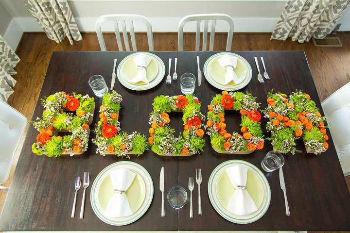 This photo provided by HGTV.com shows a tabletop with a "bloom" centerpiece made from shortly cut flowers inserted into floral foam inside of papier-mache letters whose fronts have been removed. A single letter can be used as a monogram centerpiece or letters can spell out party themes.