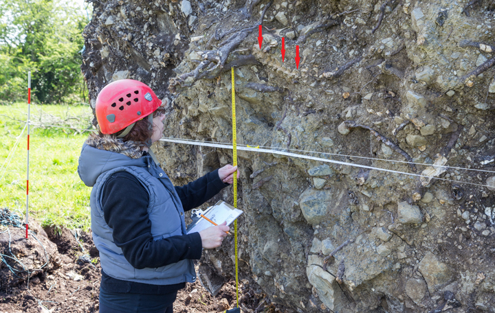 The spine of a young man from 1,000 years ago (arrows) is measured by an archaeologist.