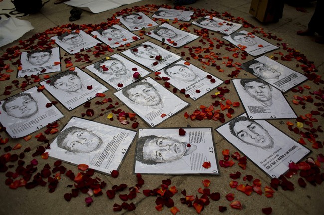 In this March 26, 2015 file photo drawings of some of 43 missing students are surrounded by flower petals, forming the shape of a heart, during a protest marking the six-month anniversary of their disappearance, in Mexico City.